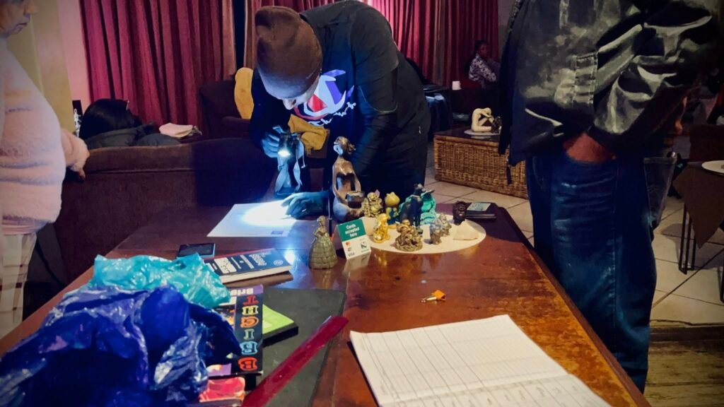 Police investigators examine documentation at a Durban massage parlour as the owner stands nearby