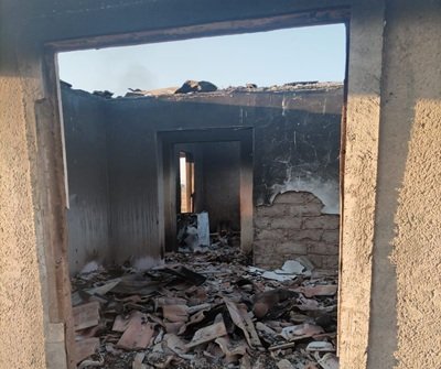 Interior view showing complete fire damage and ash-covered remains inside the house