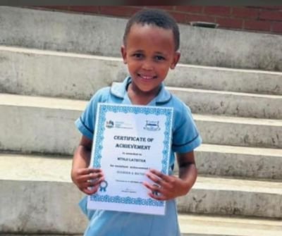 Lathitha Mtolo in her school uniform holding a certificate in Kokstad