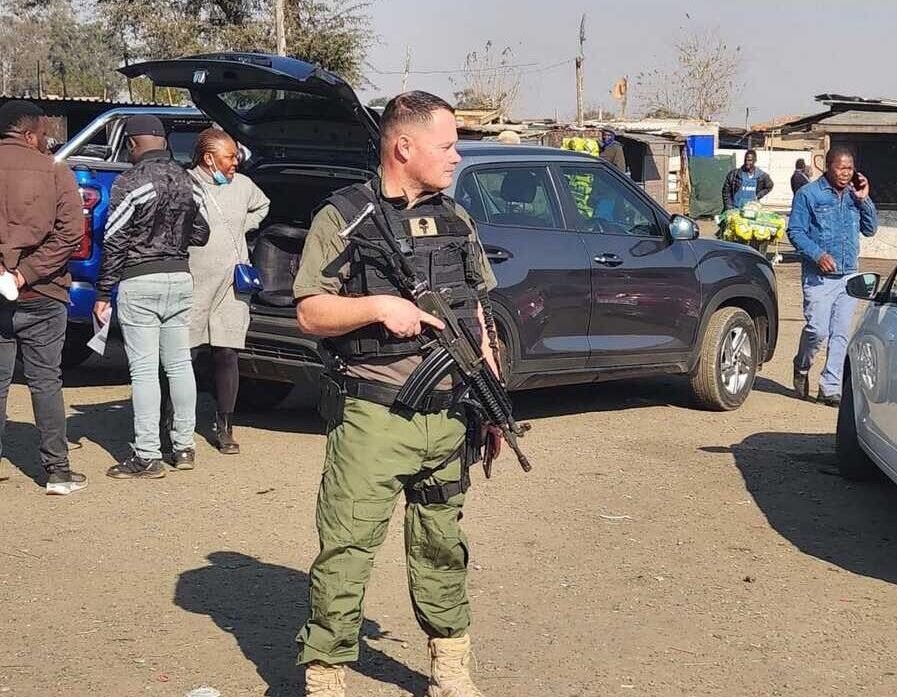 Full body photo of Marius van der Merwe, Madlanga Commission witness D, standing in a security uniform during an operation
