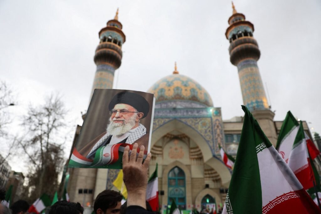 Person holding a photograph of the late Iranian president during a public gathering.